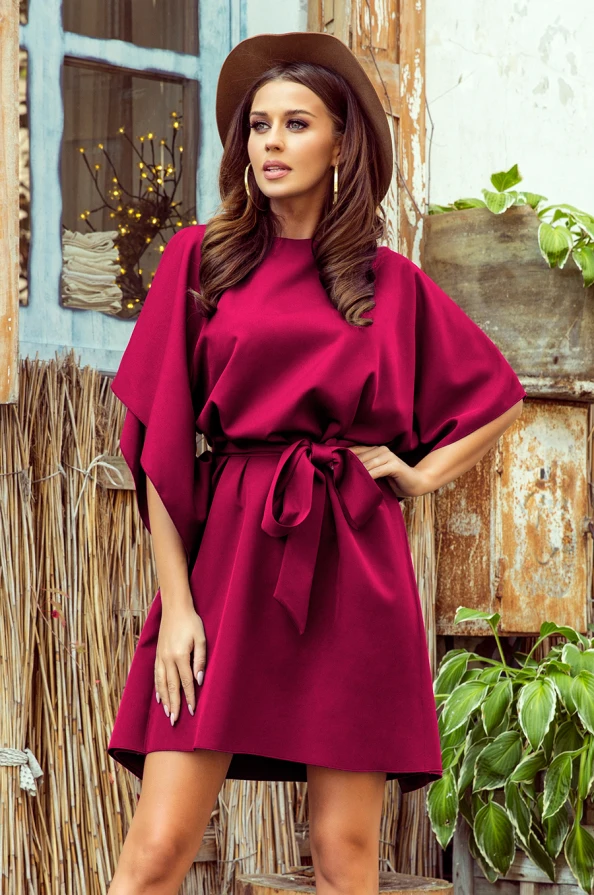 Sieviešu kleita ar brīvi krītošiem tauriņa stila piedurknēm un elegantu jostu, kas izceļ vidukli. Kleita ir piesātināti sarkanā krāsā, piešķirot tai izsmalcinātu un modernu izskatu.