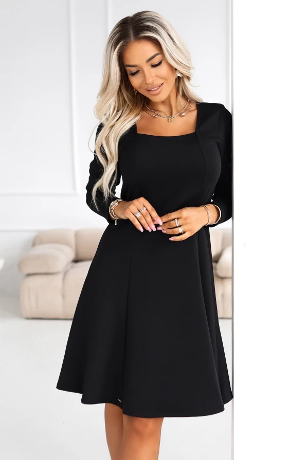 Modelka w czarnej sukience midi z dopasowaną górą i rozkloszowanym dołem