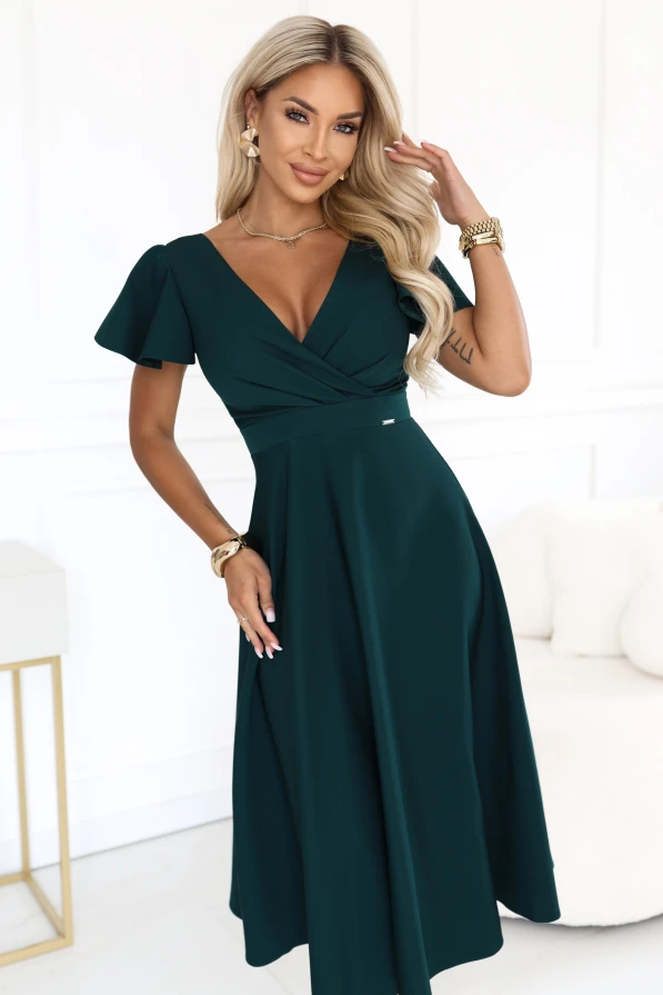 Modele valkā elegantu platinātu midi kleitu pudeles zaļā krāsā, ar pārliekamu dekoltē un īsām piedurknēm.