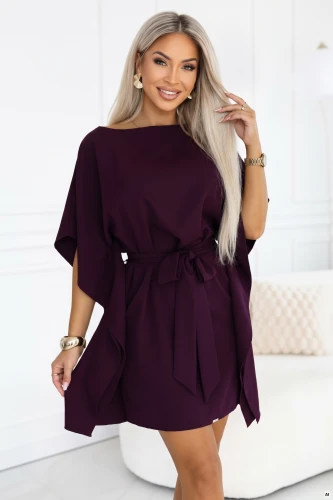 Modele Numoco kimono tipa kleitā nogatavojušās plūmes krāsā ar laivveida izgriezumu, platām piedurknēm, jostasvietā sasienamu jostu un drapētiem sāniem, garumā virs ceļiem.}