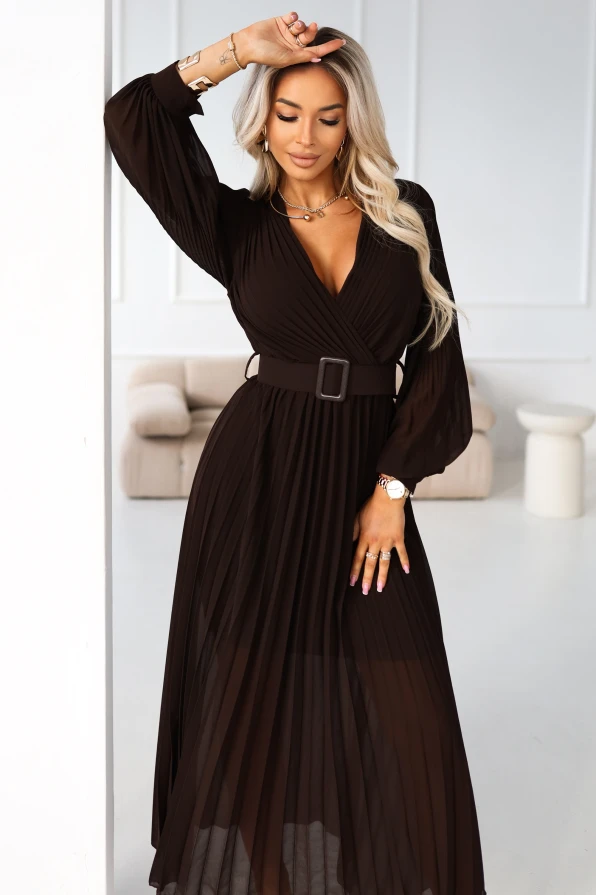 Modelka prezentuje elegancką brązową plisowaną sukienkę maxi z kopertowym dekoltem i paskiem, idealną na uroczyste okazje.