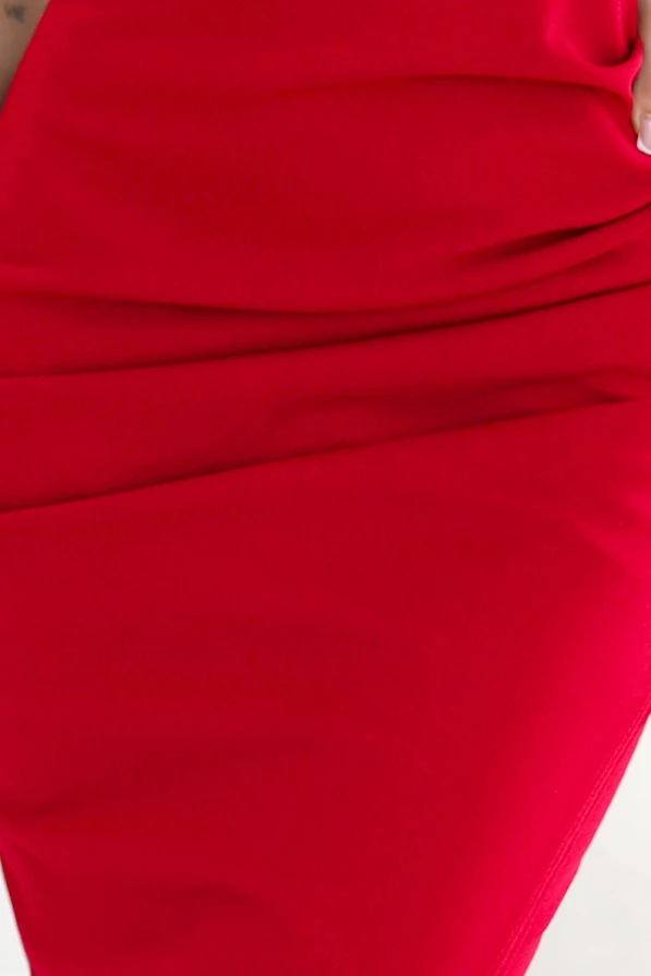 Modelka w eleganckiej czerwonej sukience midi z dekoltem, cienkimi ramiączkami i rozcięciem na nodze. Dopasowany krój podkreślający sylwetkę – Numoco Basic, produkcja europejska.